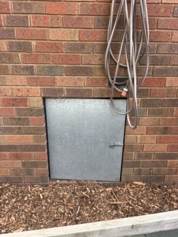 Metal access hatch in an external brick wall