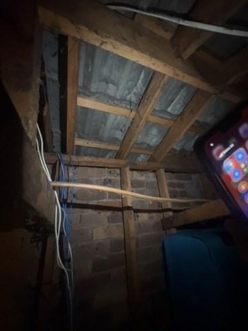 Roof-space view with timber framing, roof lining, brickwork and services